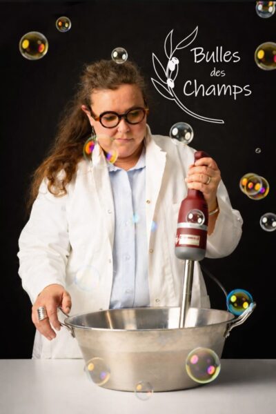 Savonnière fabriquant des savons artisanaux à l'aide d'un mixeur plongeant dans un atelier de fabrication de cosmétiques naturels.
